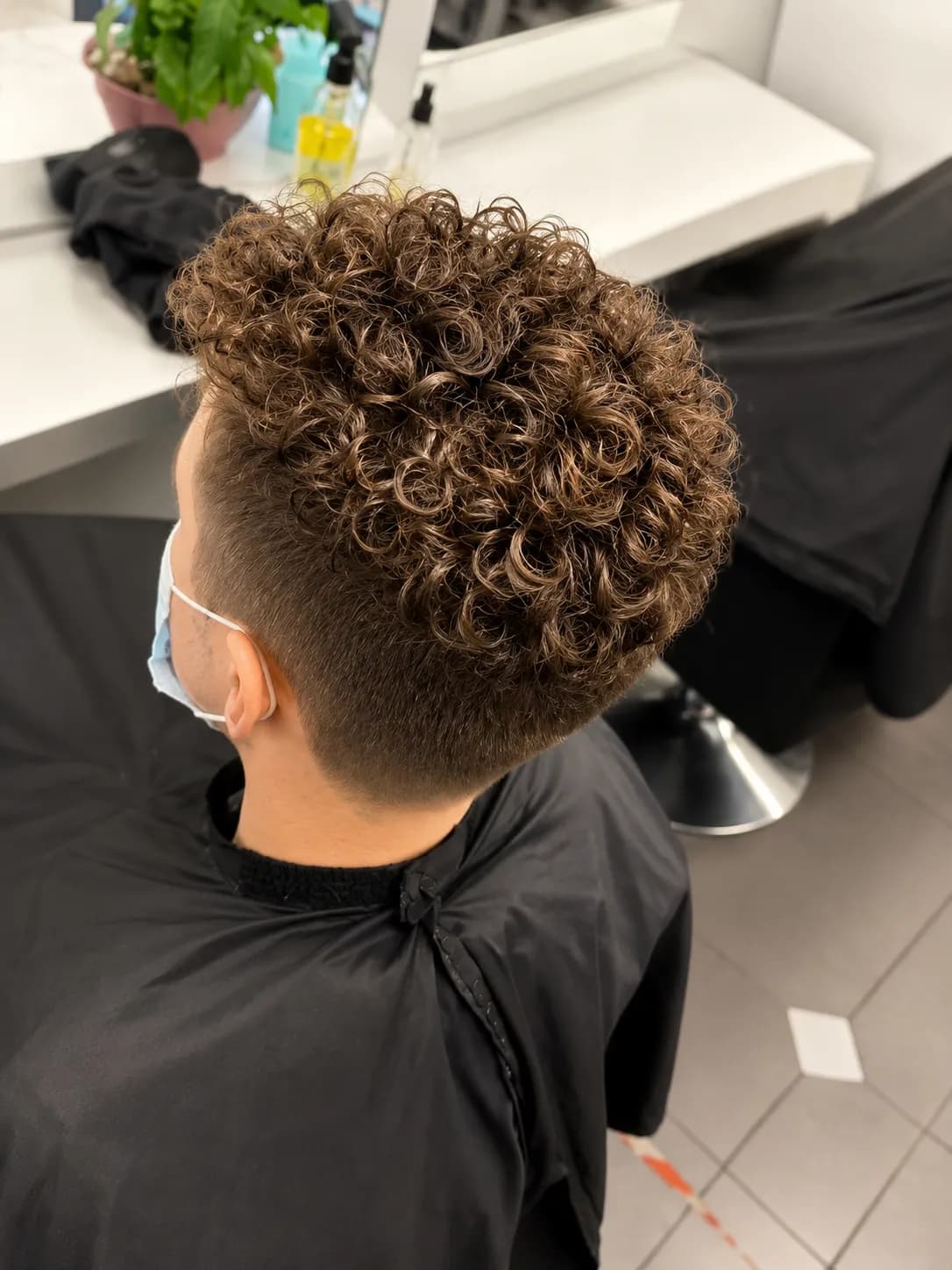 Herrenfrisur mit definierten Locken oben und sauberem Fade an den Seiten