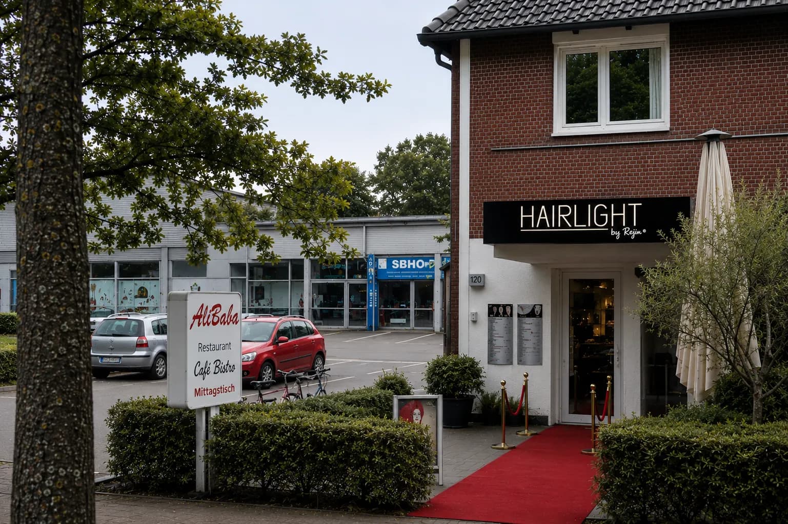 Außenansicht von Hairlight by Rejin in Oldenburg-Eversten mit rotem Teppich und HAIRLIGHT-Schild