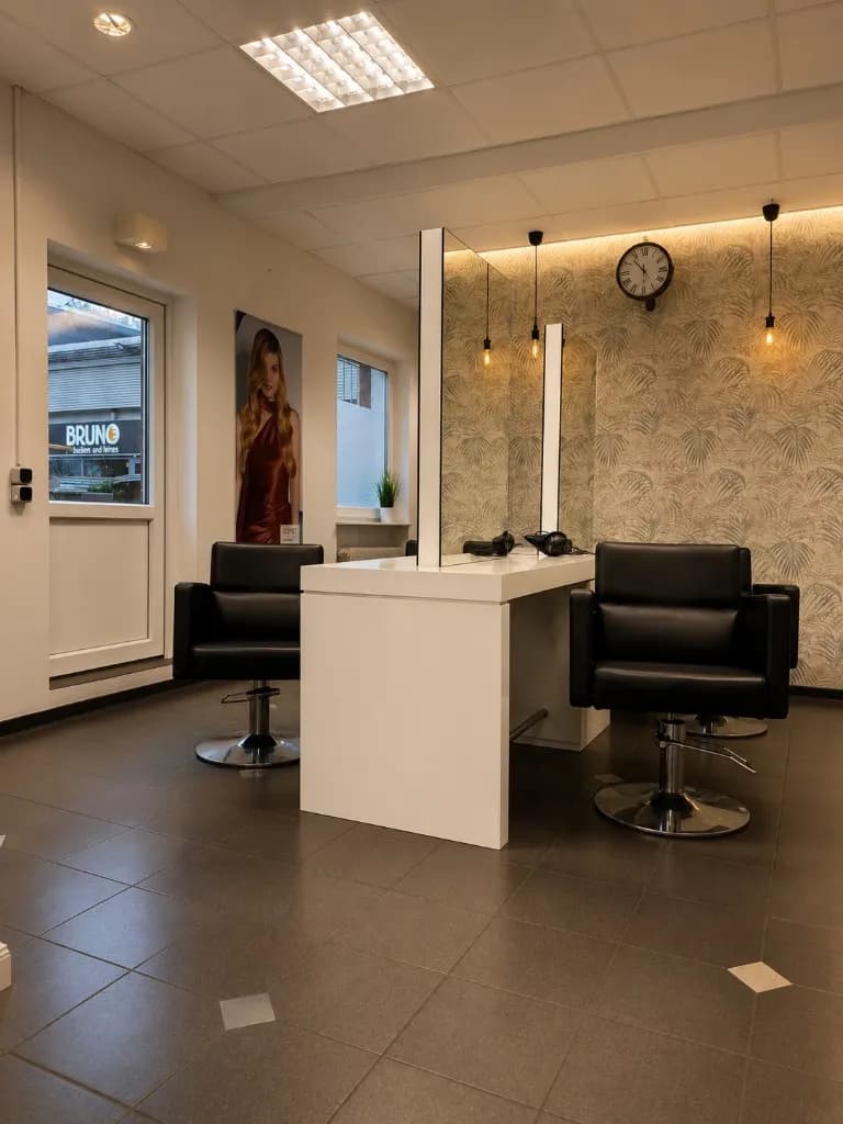 Styling-Insel mit Spiegeln, Pendelleuchten und schwarzen Friseurstühlen